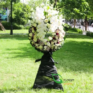 White and purple funeral flower arrangement with roses and orchids